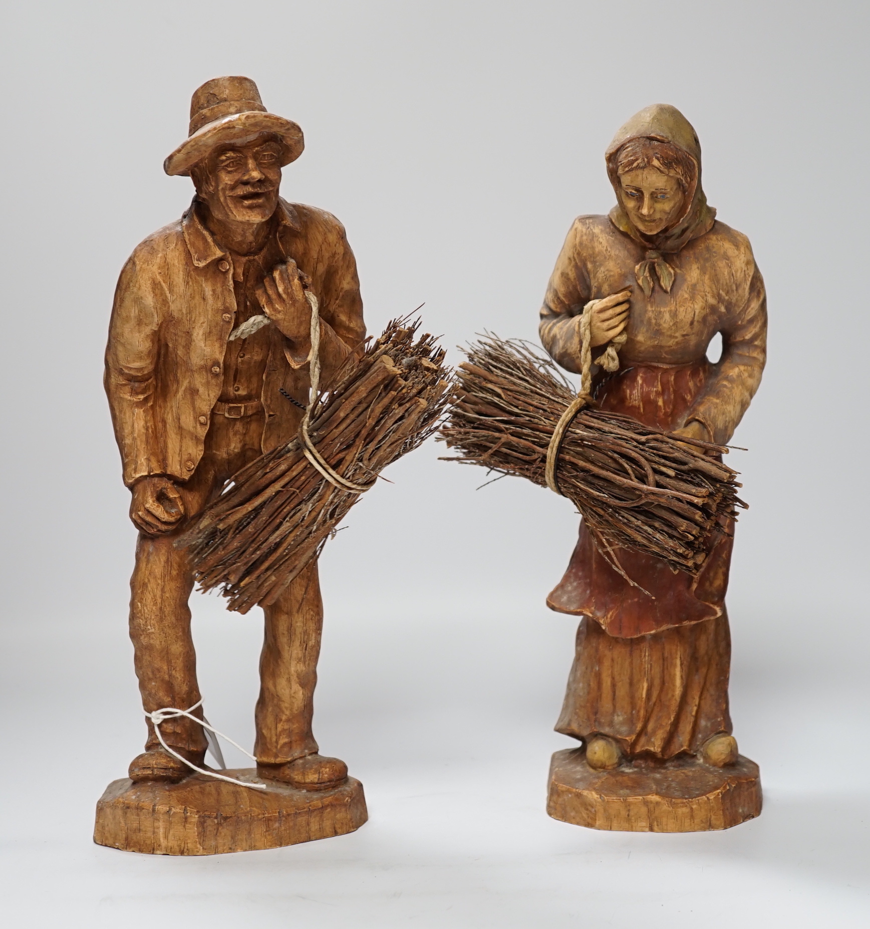 A pair of composition peasant figures gathering firewood, tallest 33cm